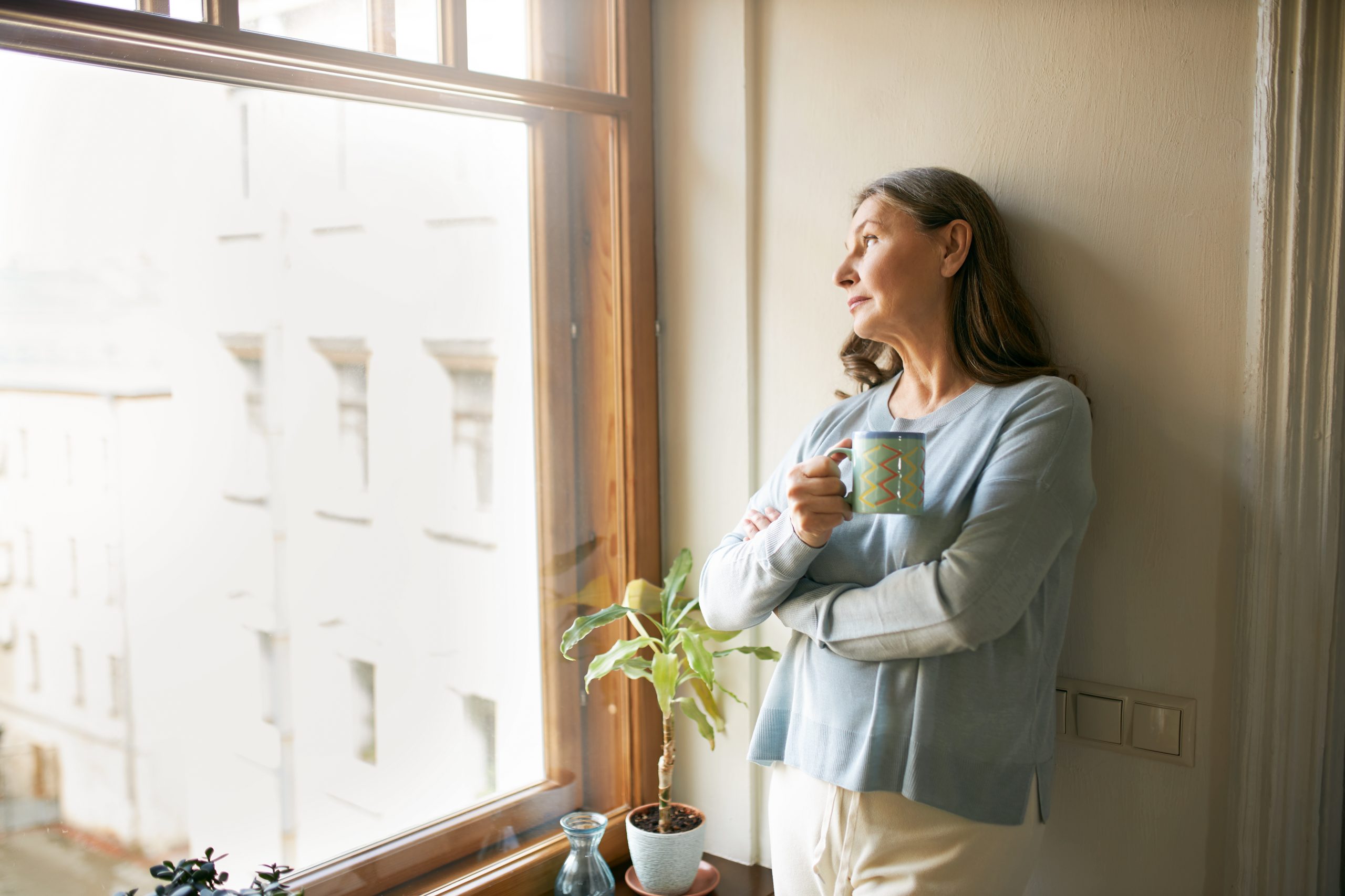Portrait,Of,Thoughtful,Retired,Mature,Woman,In,Casual,Clothes,Standing woman looking out window
